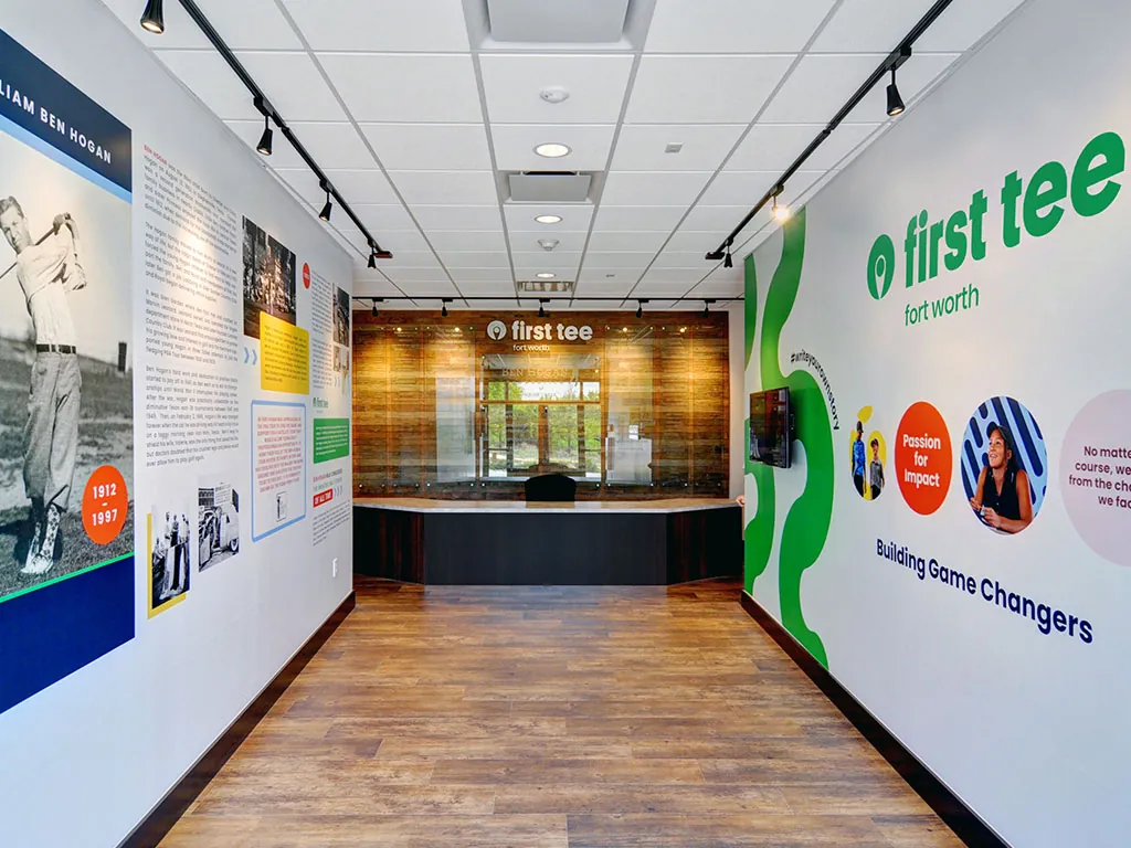 Ben Hogan Learning Center main hall with the Ben Hogan biographical wall, reception desk, and First Tee 'Building Game Changers' branded wall