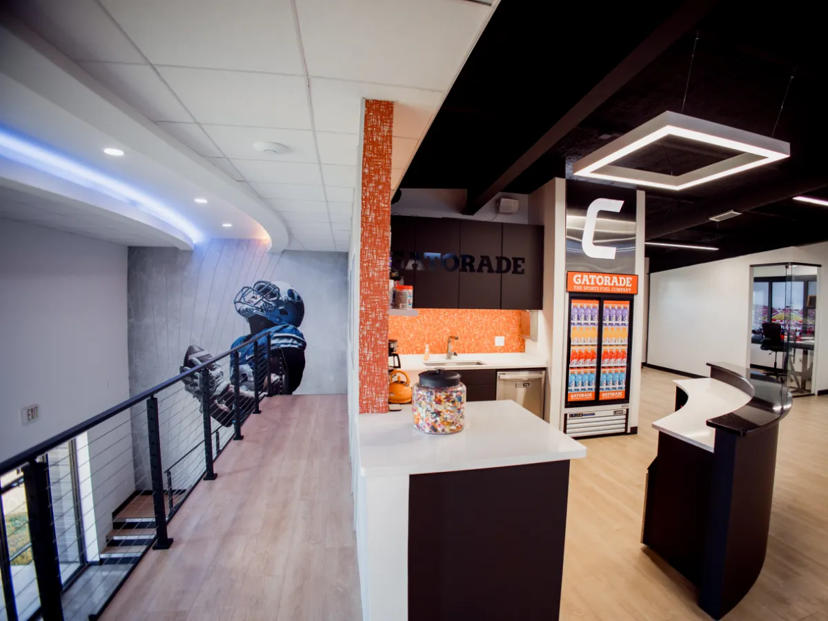 Champion Sports Construction office showing the football player vinyl wall, Gatorade-stocked kitchen, the dimensional C logo, and the reception area