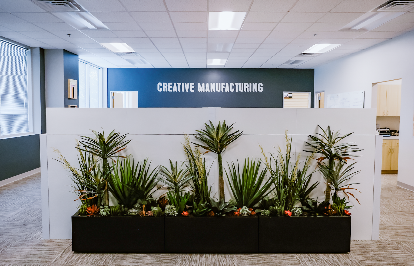 Creative Manufacturing reception area with custom planters in front of a Creative Manufacturing branded vinyl wall graphic