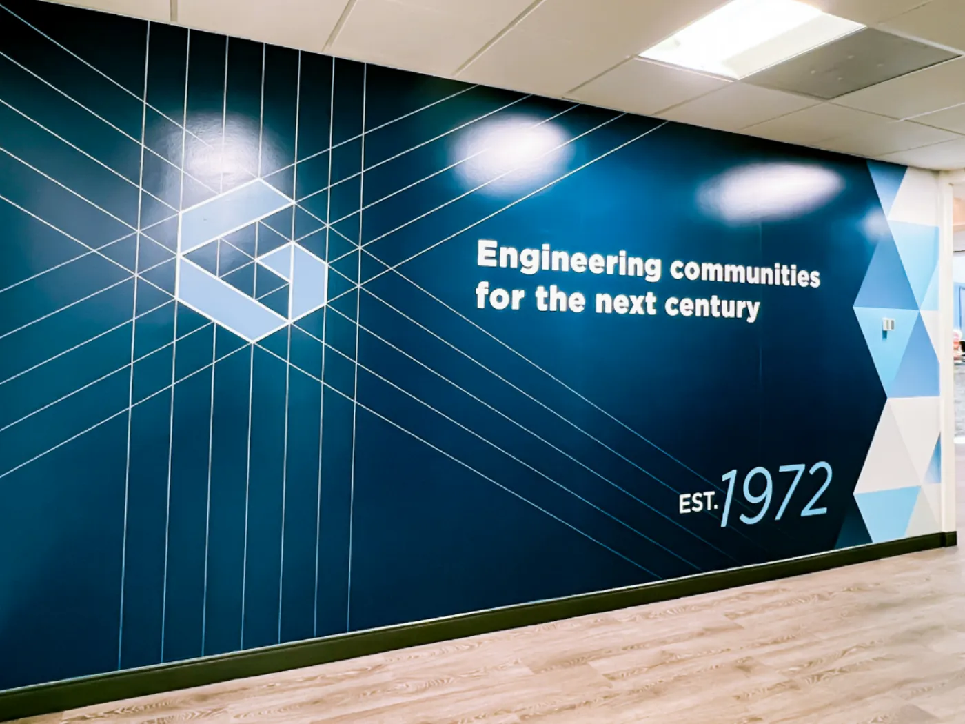 Engineering communities for the next century mural with isometric line drawings of the G mark and EST. 1972 text on a deep navy wall