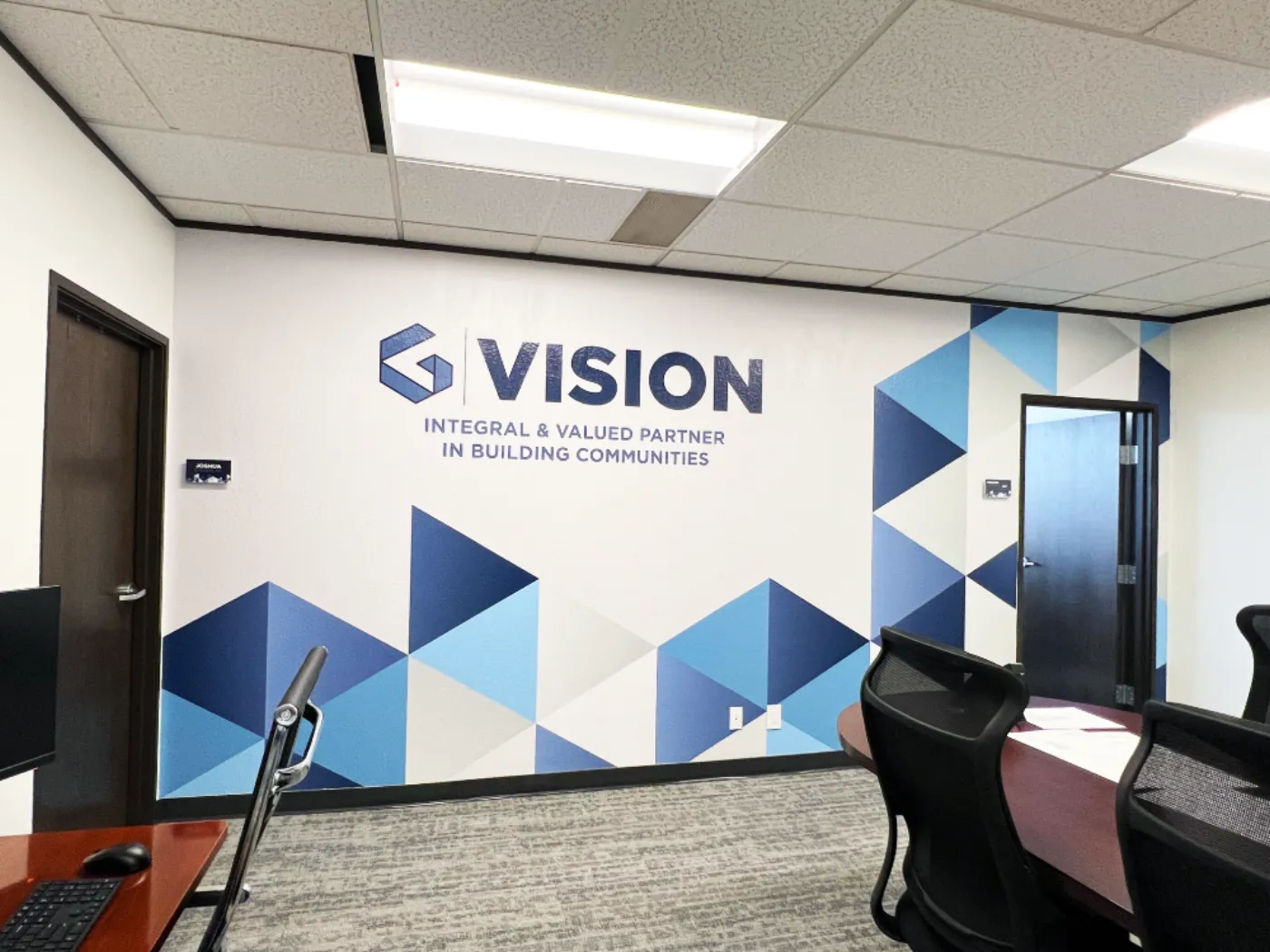 Graham Associates VISION wall featuring the G mark, an Integral and Valued Partner in Building Communities tagline, and a triangle pattern install