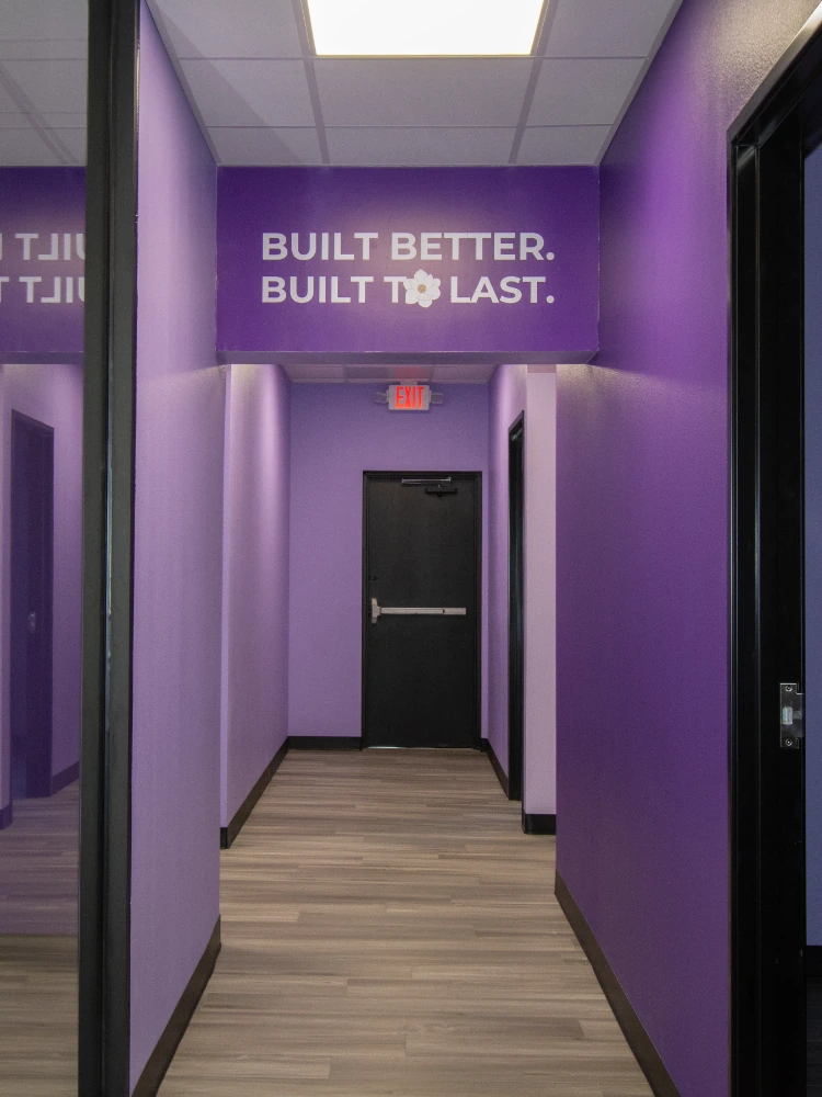 Custom vinyl banner reading 'Built Better. Built to Last.' mounted above the entrance to the office's purple corridor