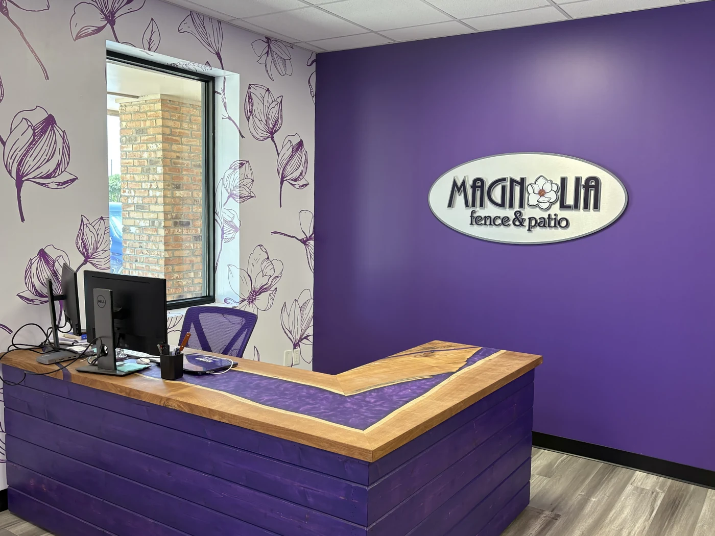 Custom dimensional oval Magnolia Fence & Patio logo plaque on a purple wall
