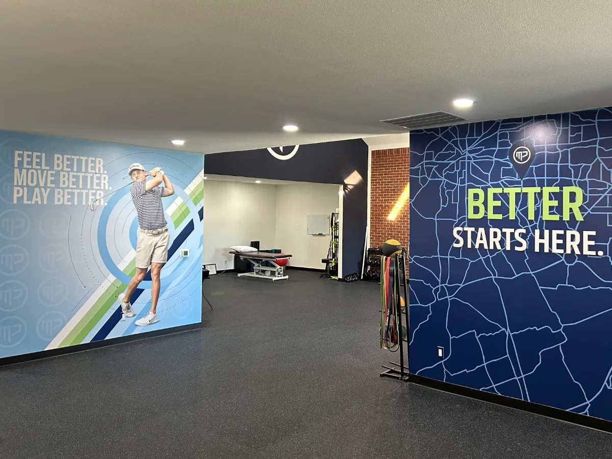 Close-up of the MyPhysio 'Feel Better. Move Better. Play Better.' vinyl wall with a life-size golfer mid-follow-through