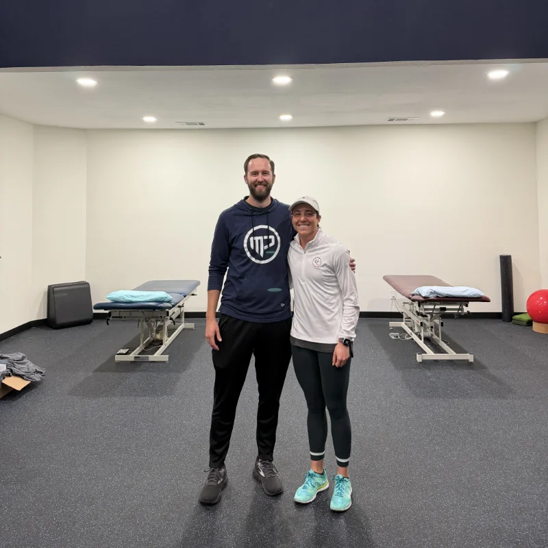 Jared Cave, owner of MyPhysio, standing with Uptimize Design founder Camry Tardy beneath the studio's custom acrylic MP logo sign