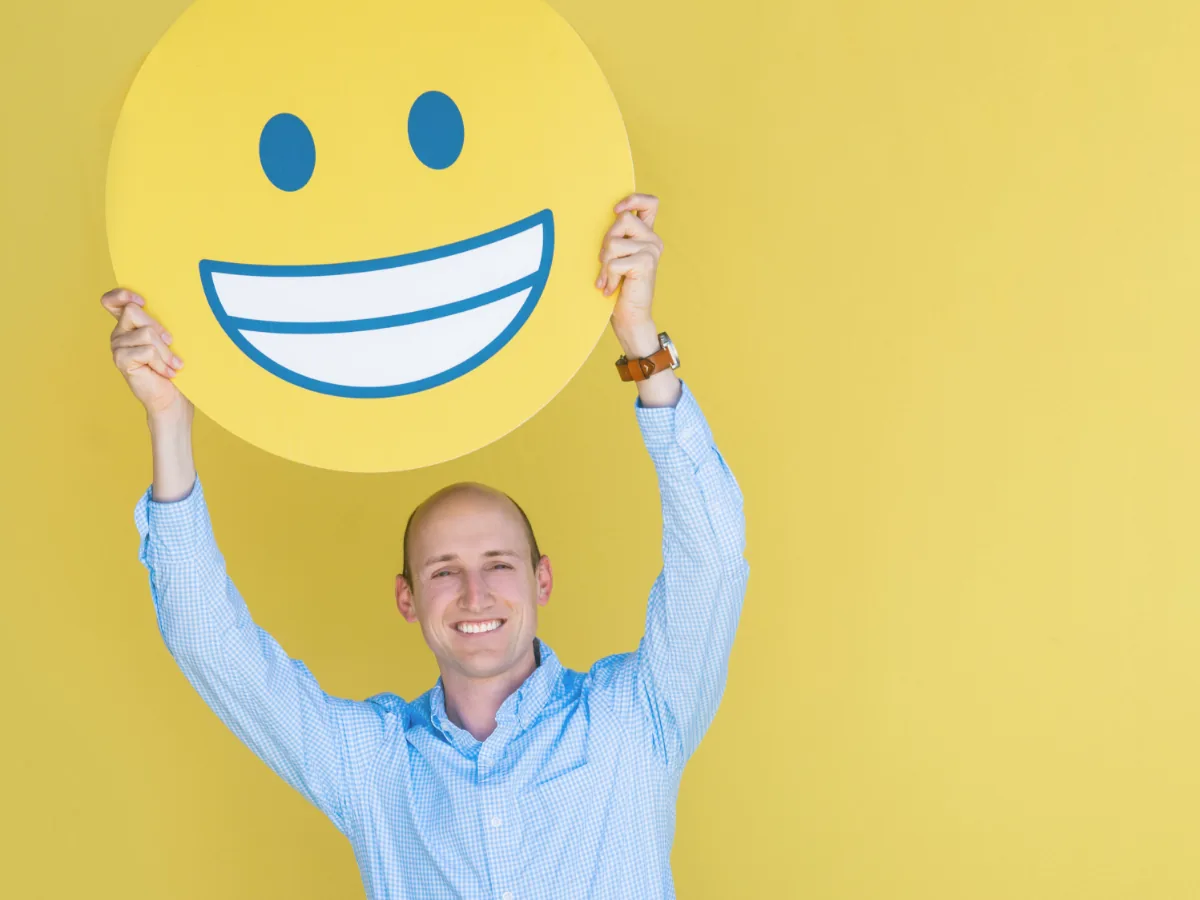 Dr. Calvin Tardy holding a large smiley face cutout against a yellow background during a Tardy Orthodontics branding photo shoot