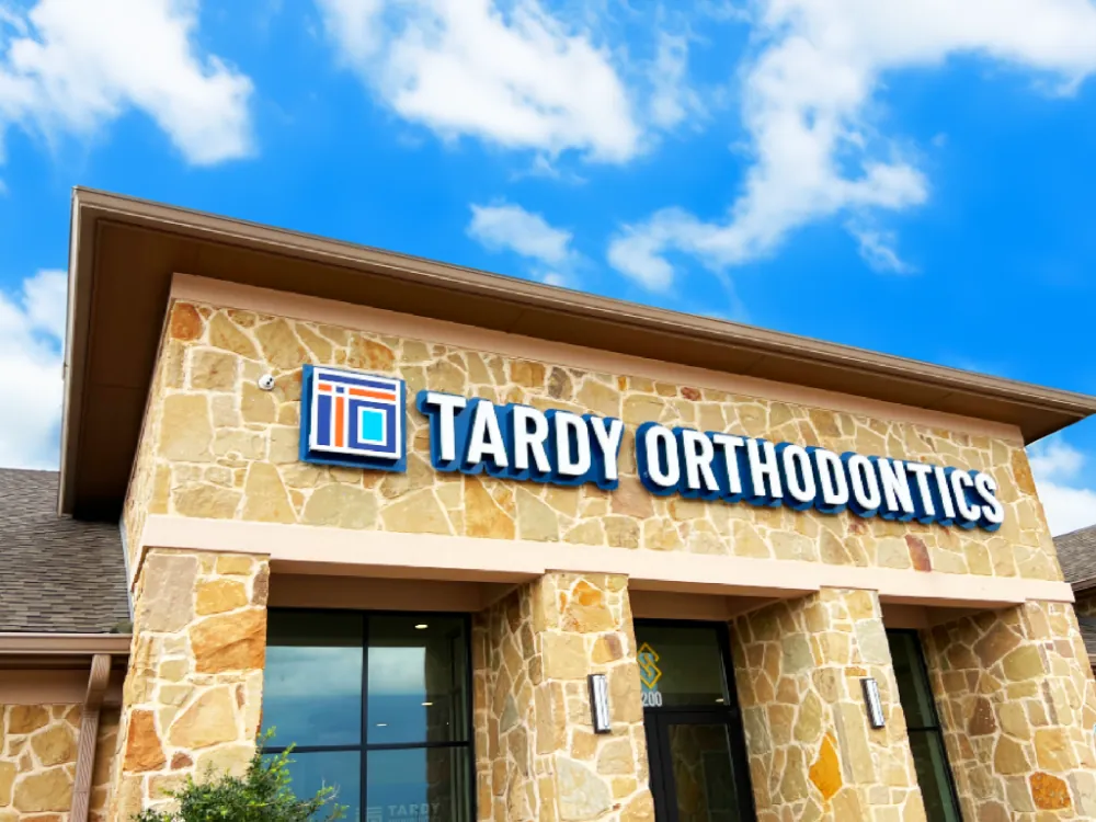 Tardy Orthodontics North Richland Hills office exterior with the dimensional brand sign mounted on a stone facade under a blue sky